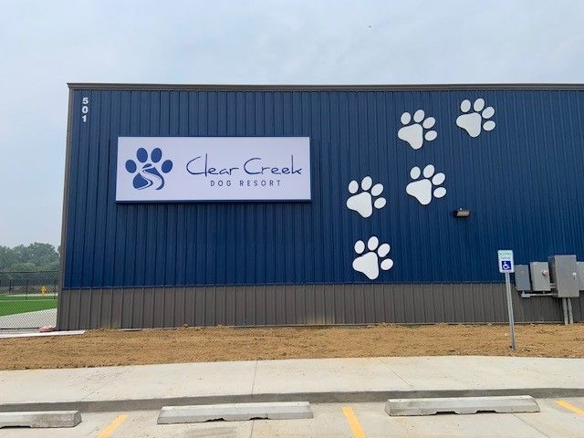 Clear Creek Dog Resort building with blue exterior, paw prints, and a sign.
