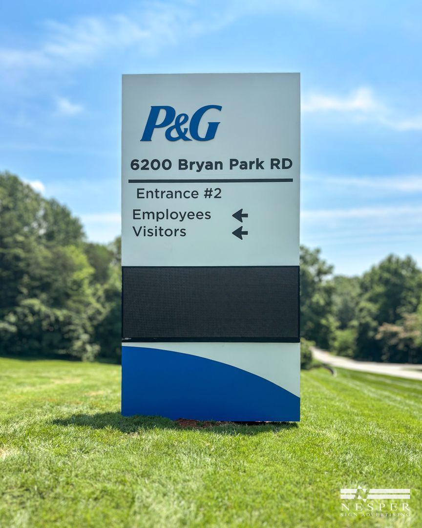 Sign for P&G at 6200 Bryan Park Rd. Directs to entrance #2, with arrows for employees and visitors. Green grass, blue sky.