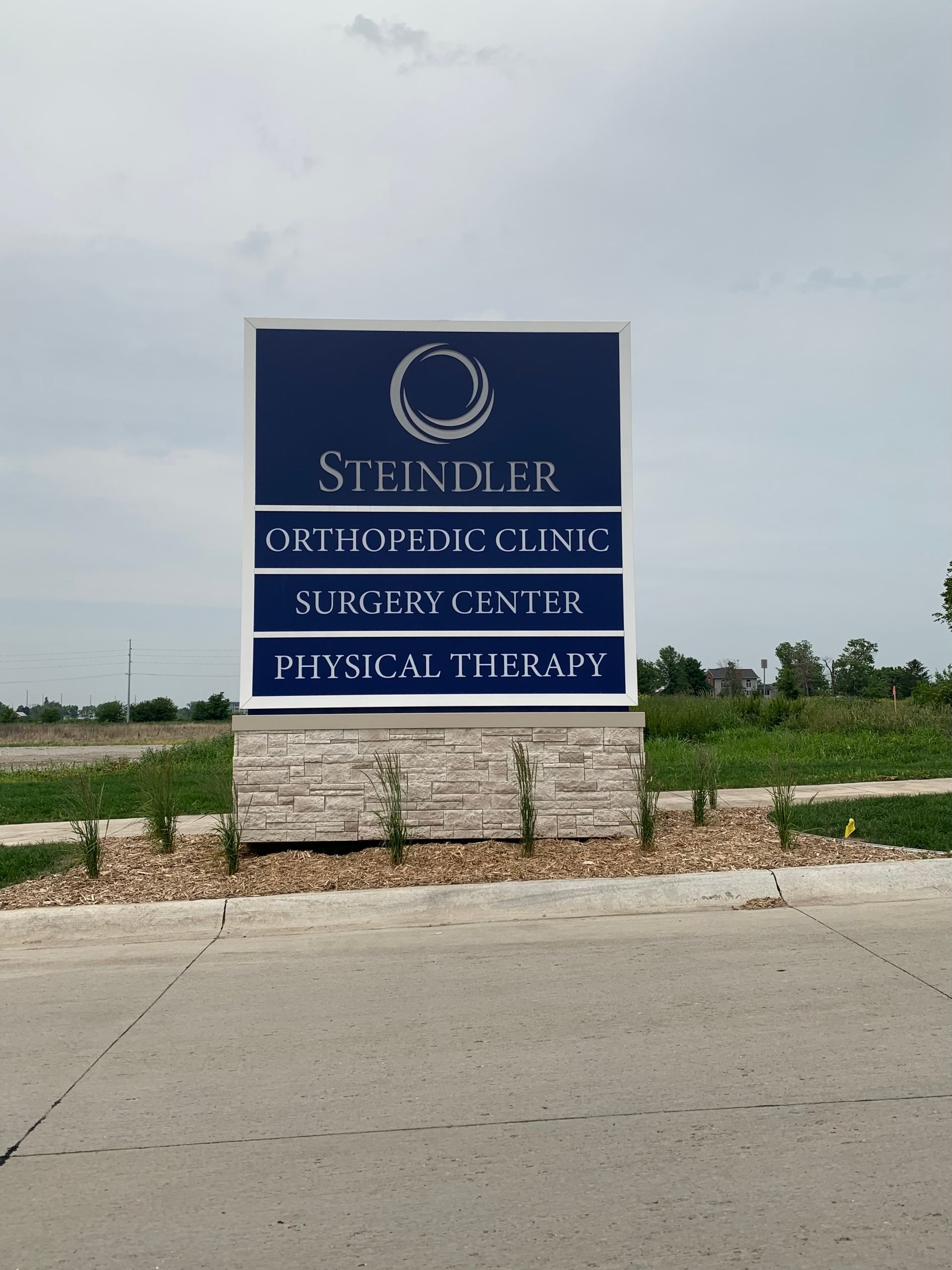 Sign for Steindler Orthopedic Clinic, Surgery Center, and Physical Therapy. Navy blue with white text, on a brick base.