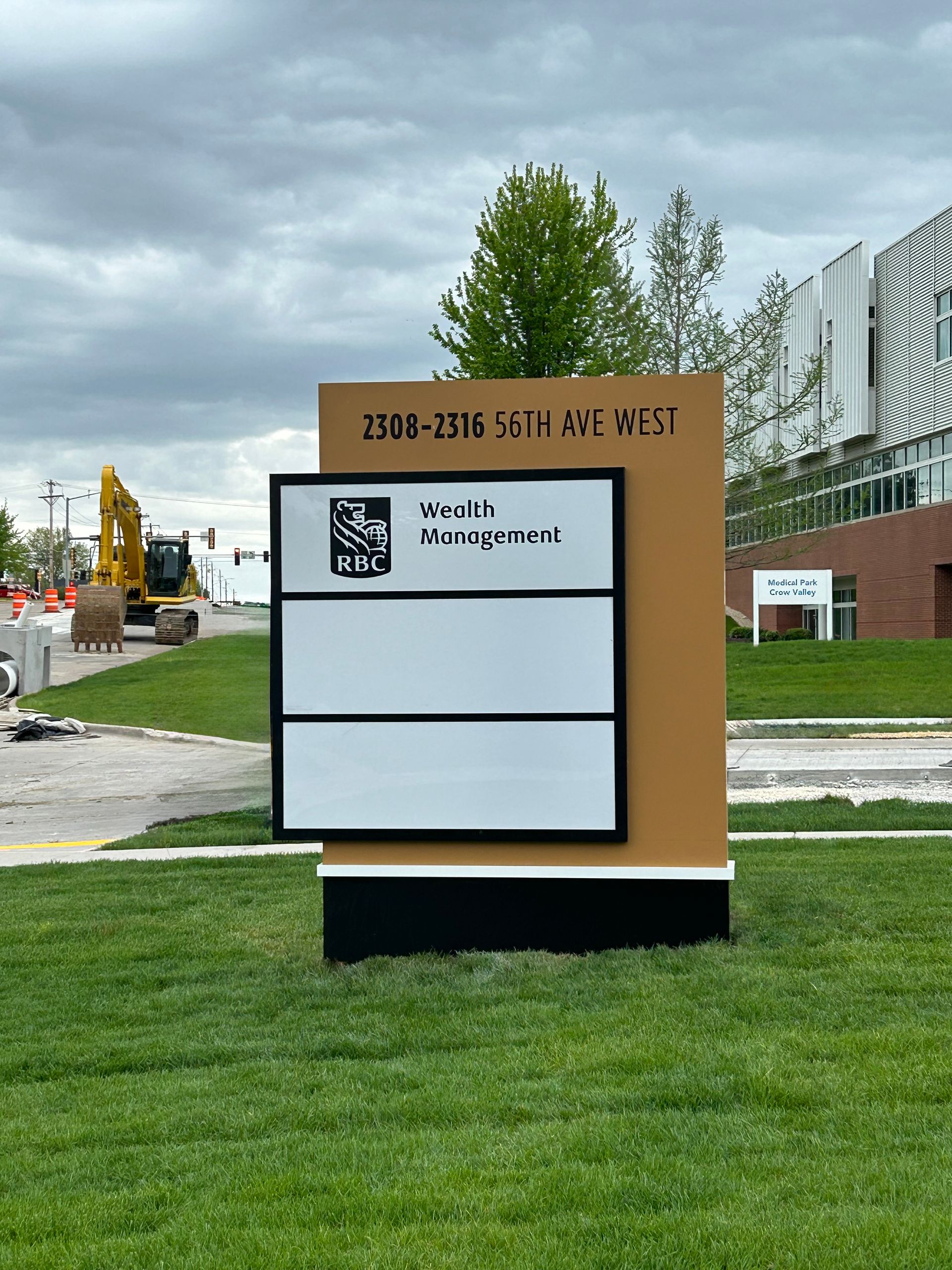 Sign for Sports Campus with blank panels, brown backdrop, and construction in background.
