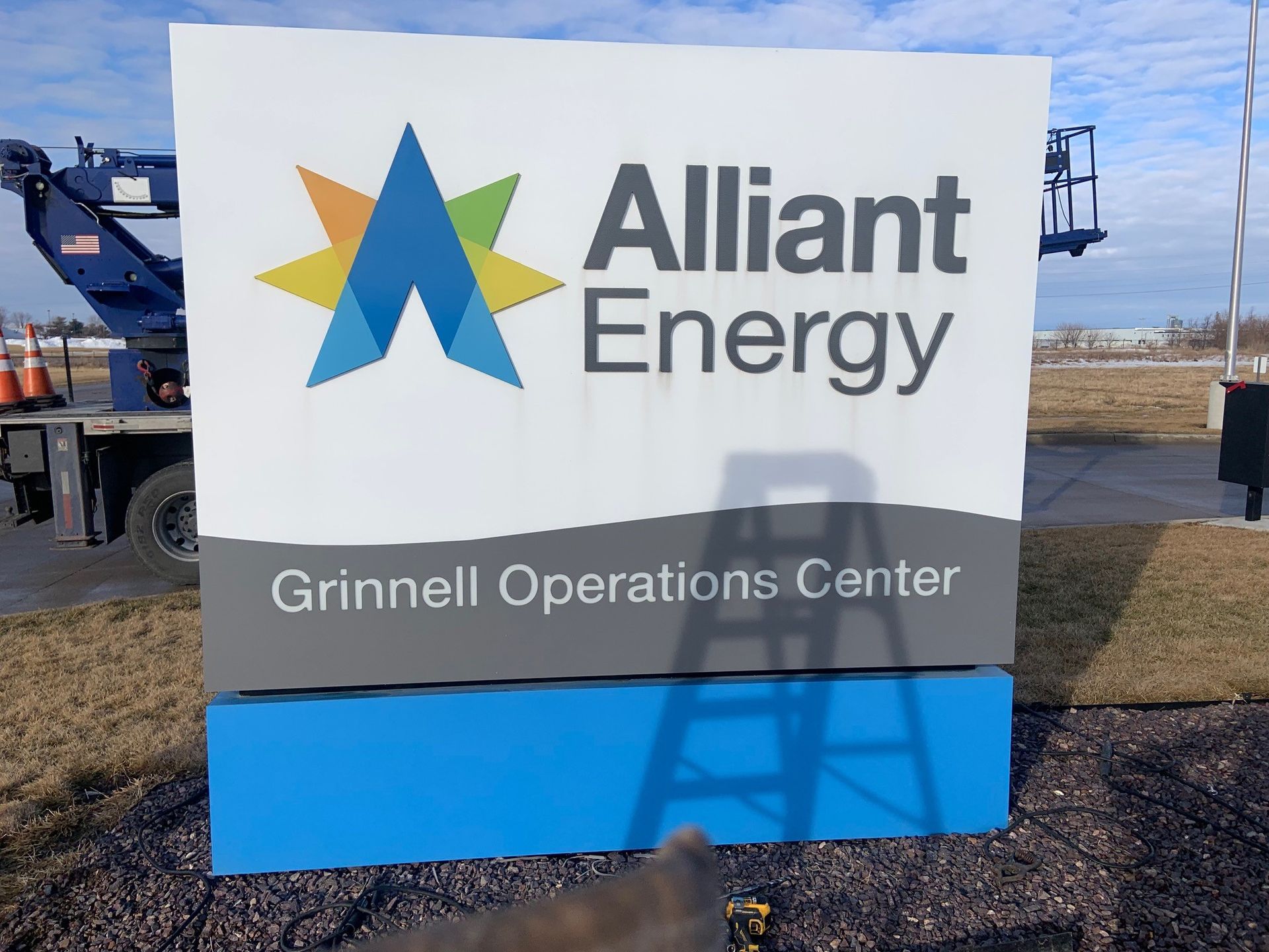 Sign for Alliant Energy, Grinnell Operations Center. White background with logo and text. Blue and gray sections at bottom.