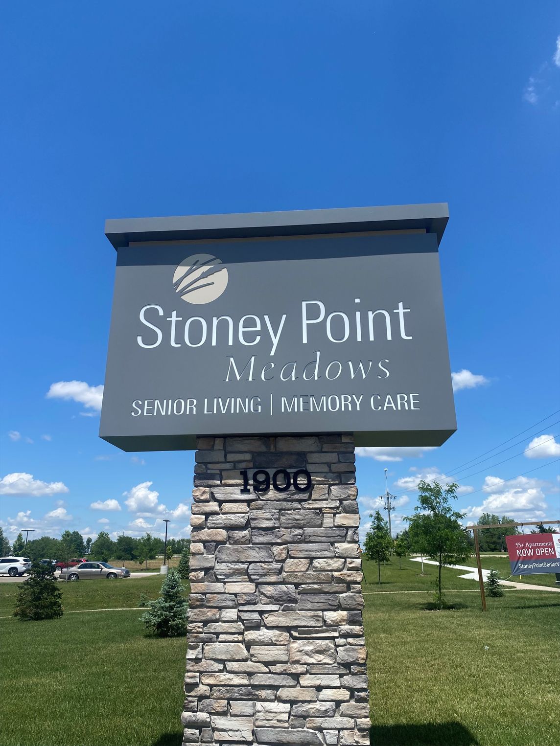 Sign for Stoney Point Meadows Senior Living & Memory Care, on a stone pillar, with address 1900. Sunny day, blue sky.