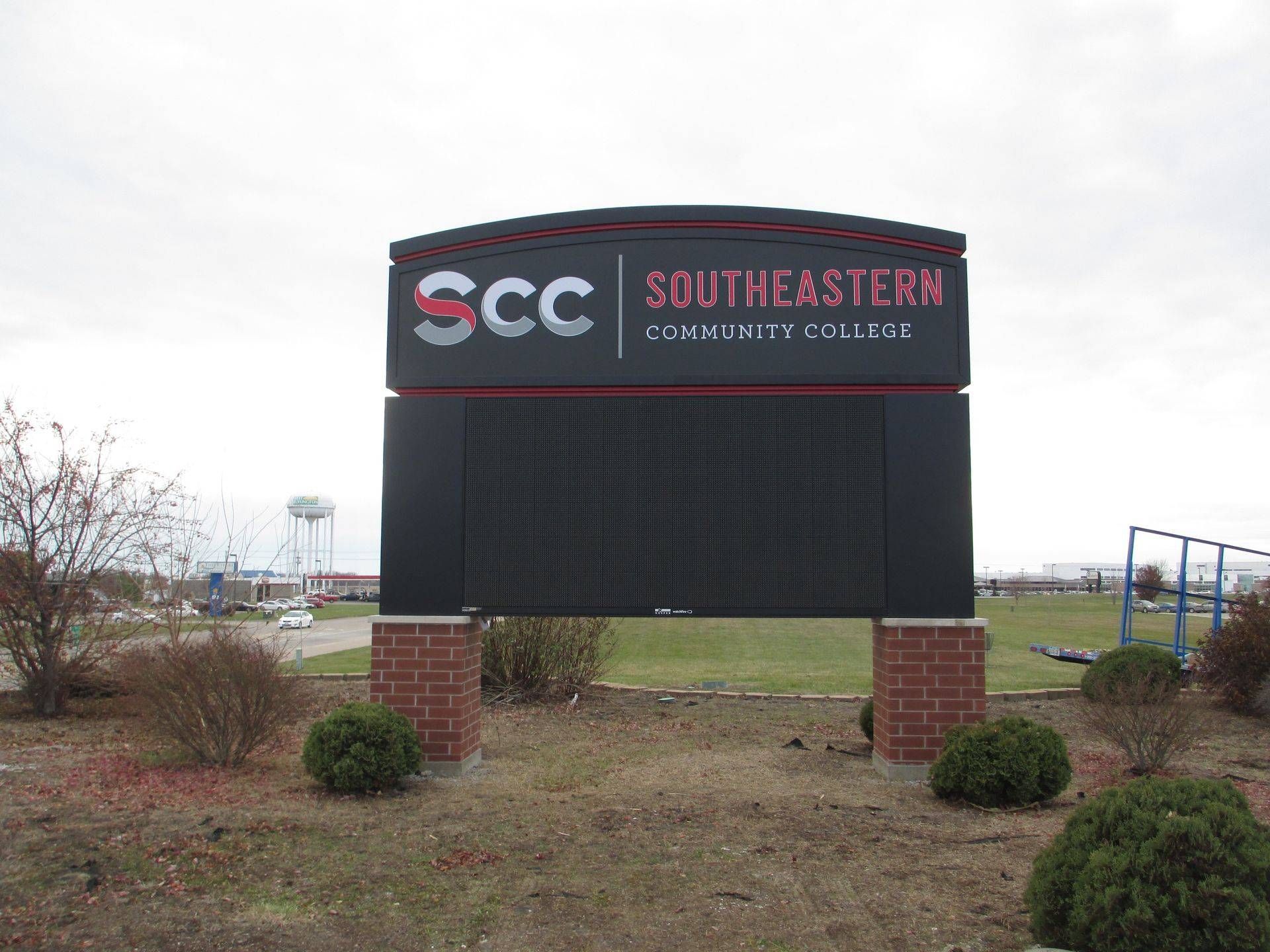 A large sign for Southeastern Community College is sitting in the middle of a field