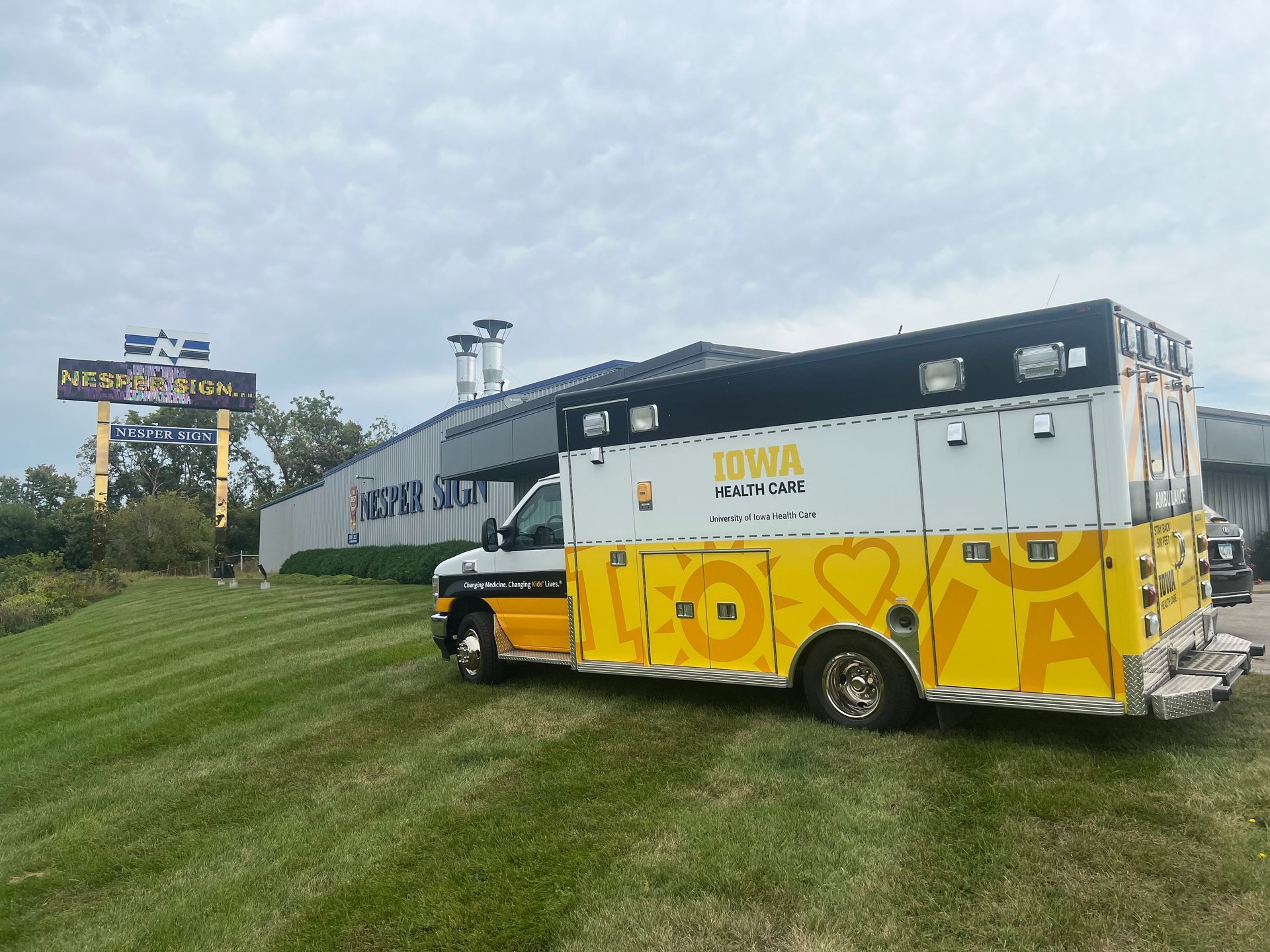 A yellow and white ambulance is parked in front of a building.