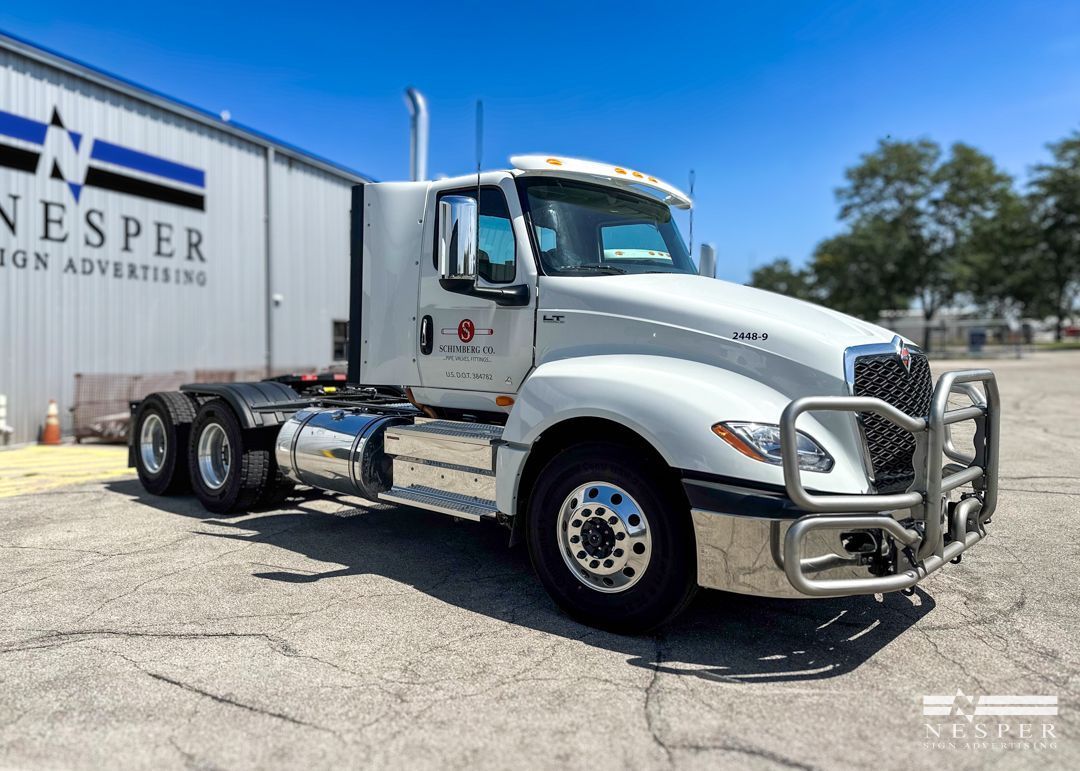 A white semi truck is parked in front of a building.