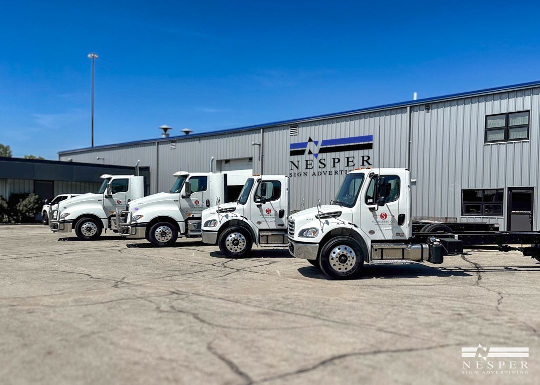A row of white trucks are parked in front of a building.