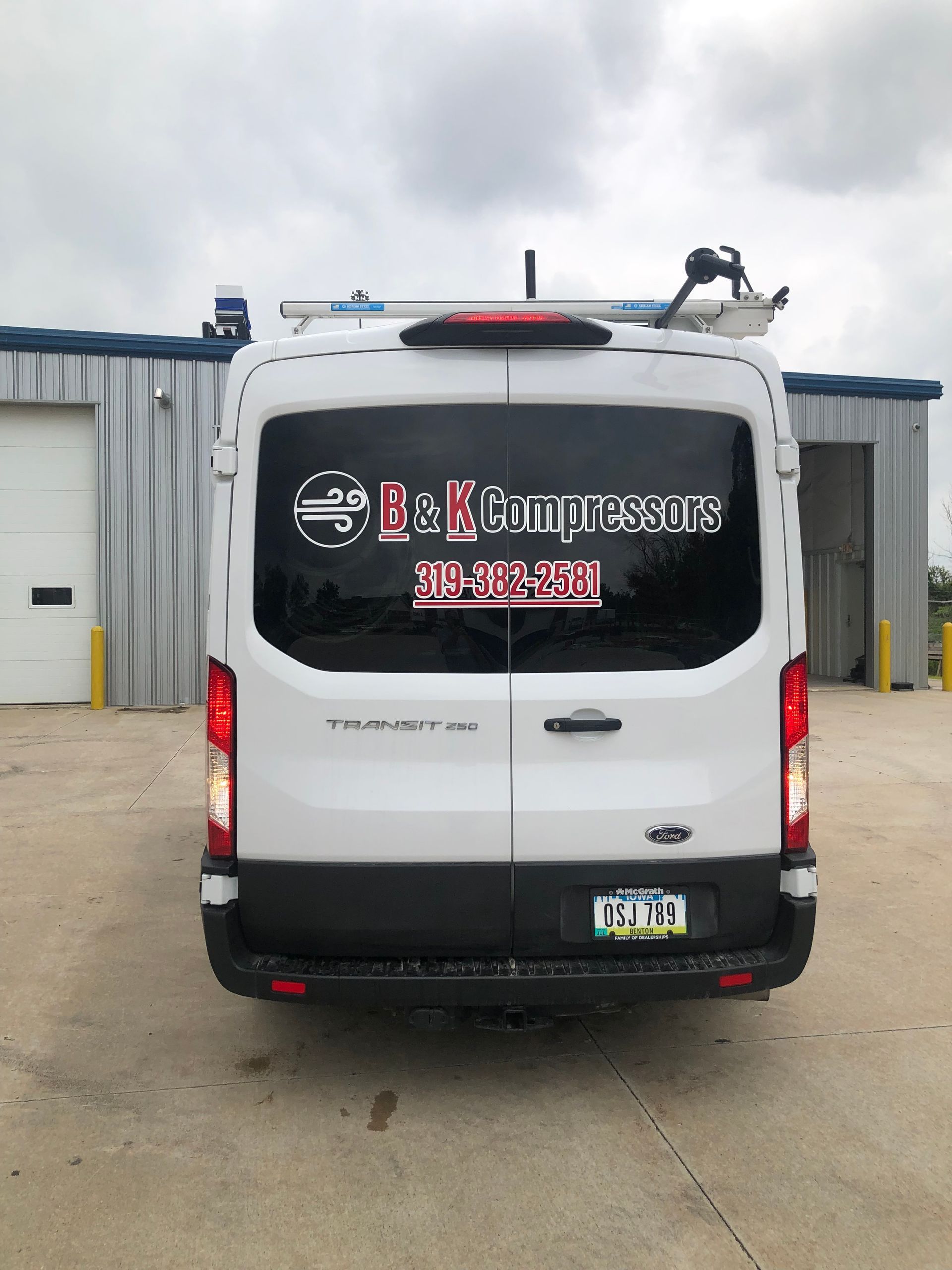 A white van B & K Compressors is parked in front of a building.