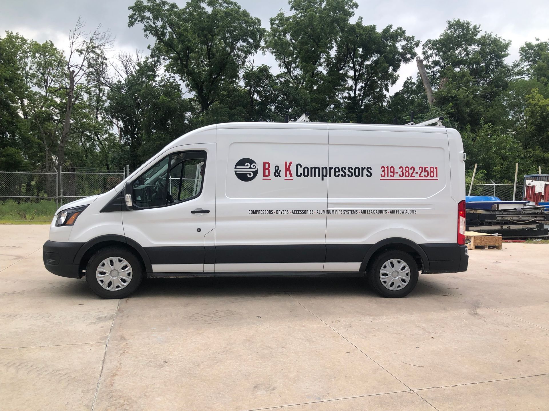 A white van with the words b & k compressors on the side is parked in a parking lot.