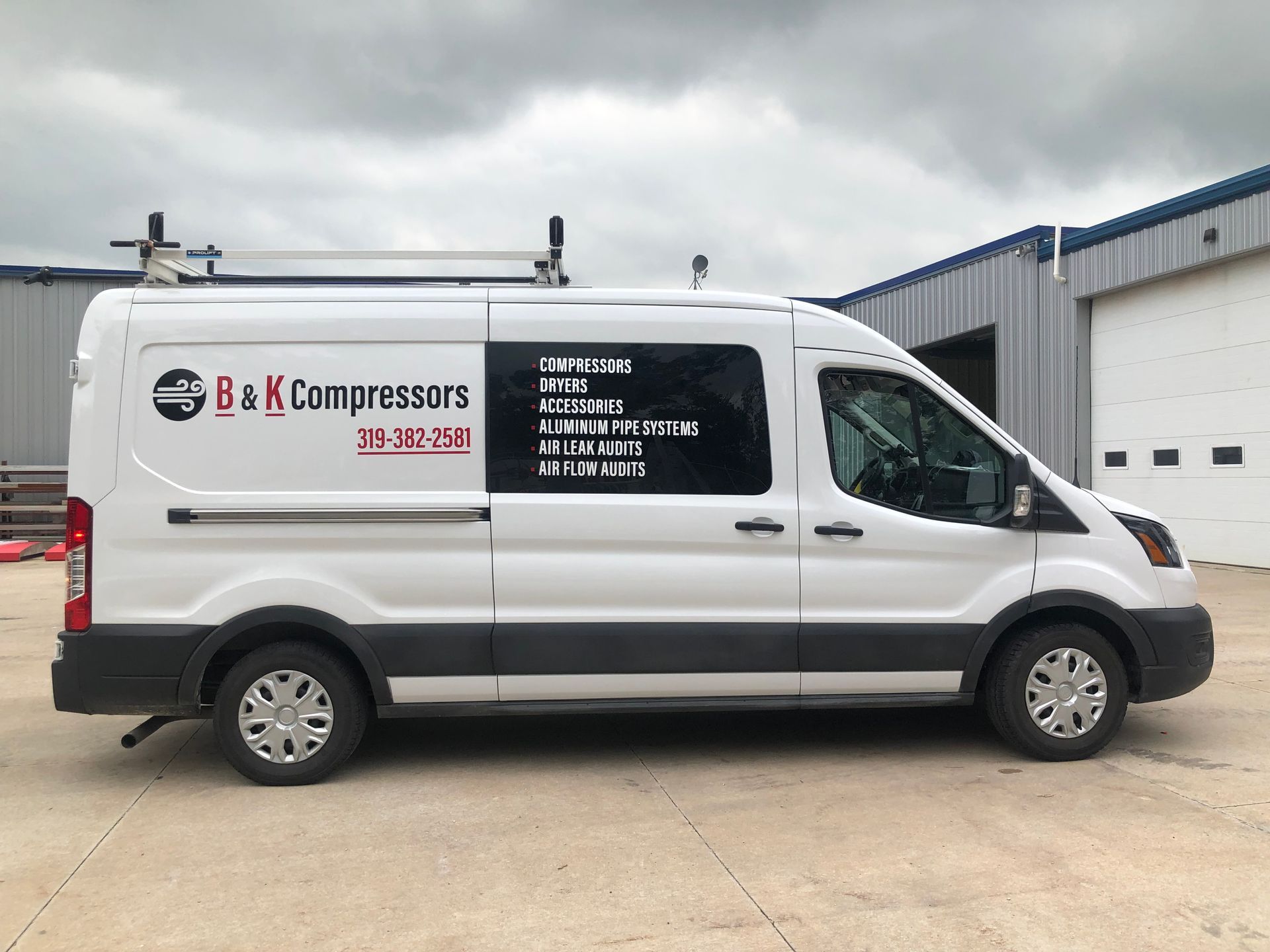 A white van is parked in front of a building.