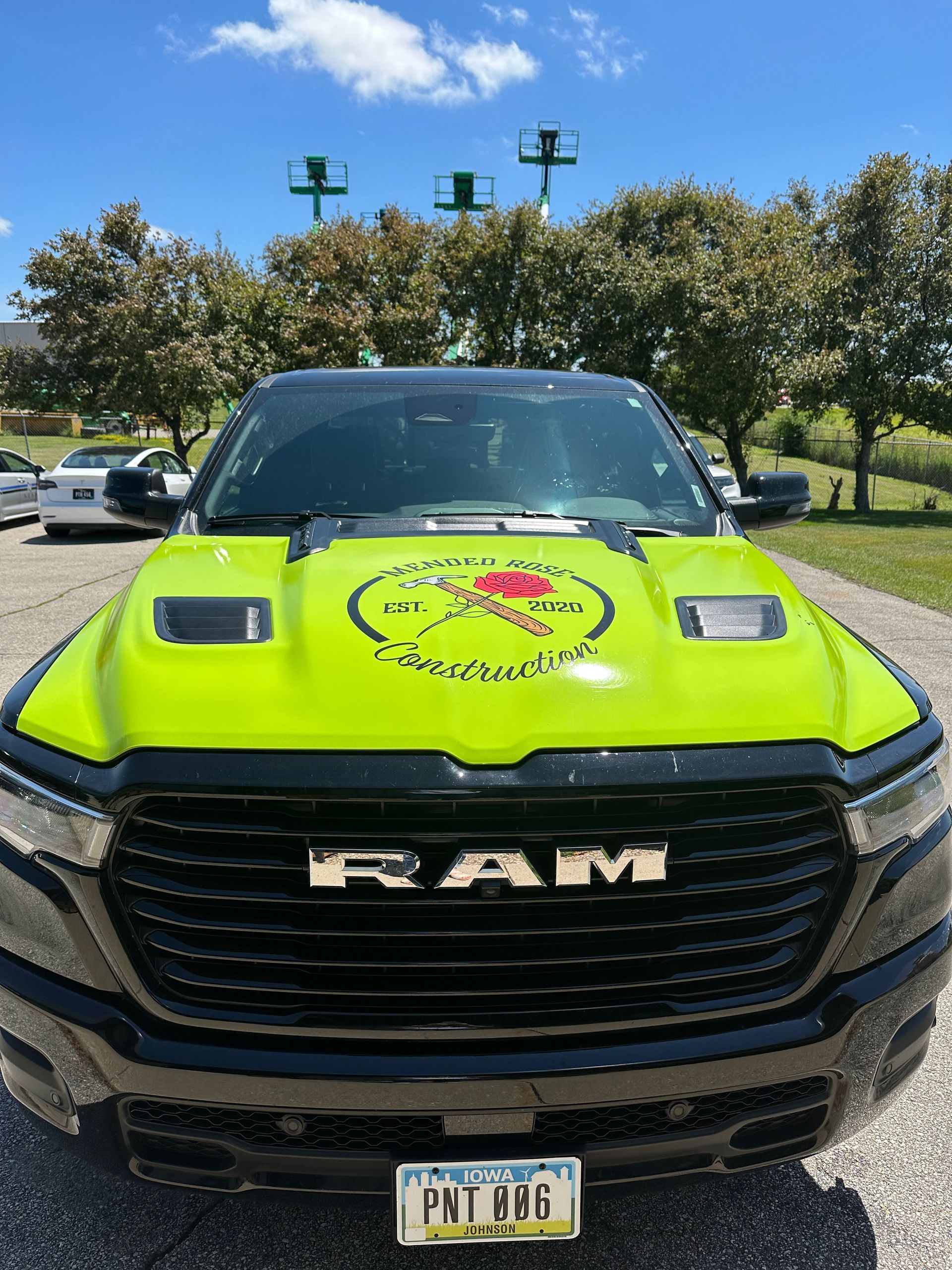 Lime green and black RAM truck with logo on the hood, parked outdoors.