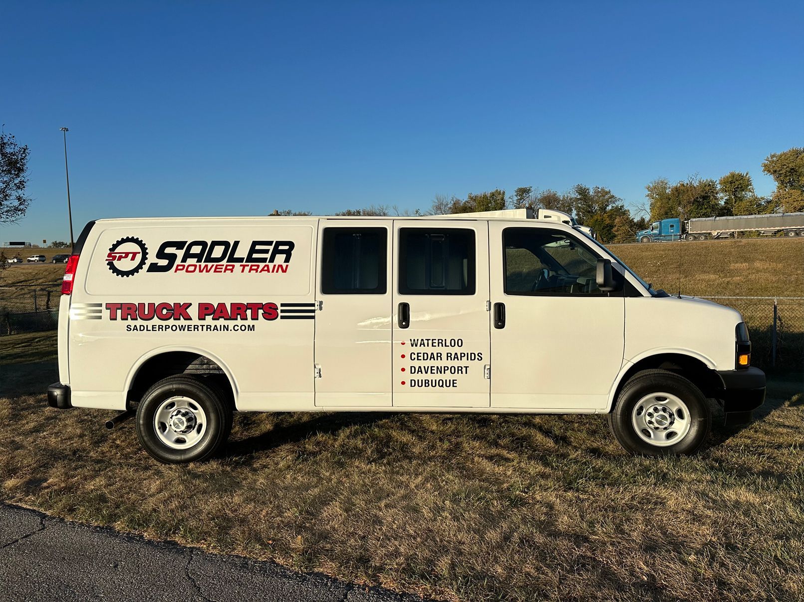 White van with 'Sadler Motor Parts' logo parked on grassy area.