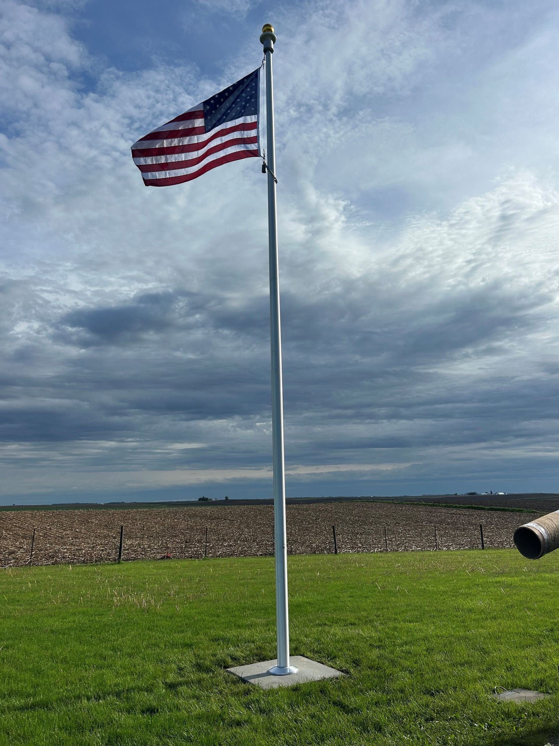 An American flag is flying in the wind on a pole in a field.