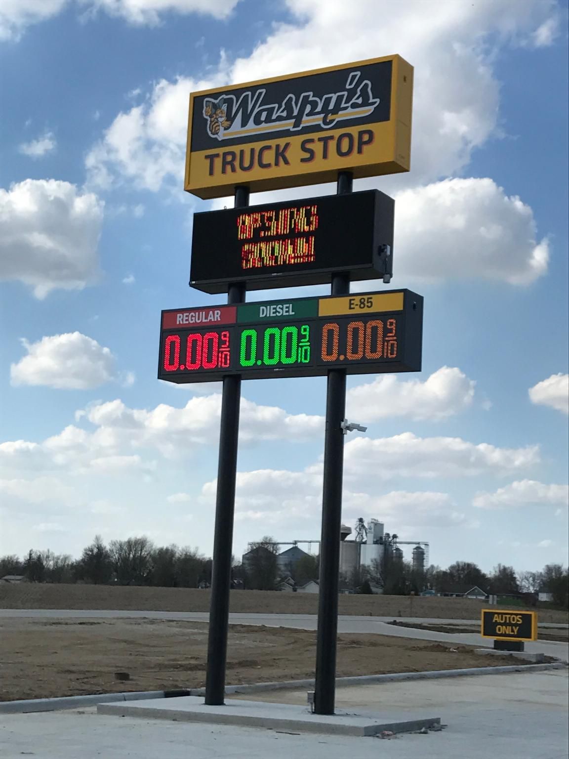 A sign for wagne 's truck stop with a blue sky in the background