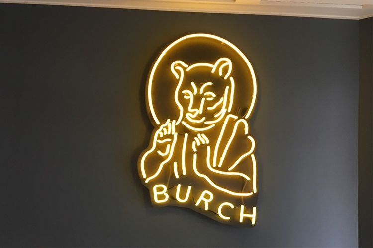 A neon sign that says Burch with a bear on it