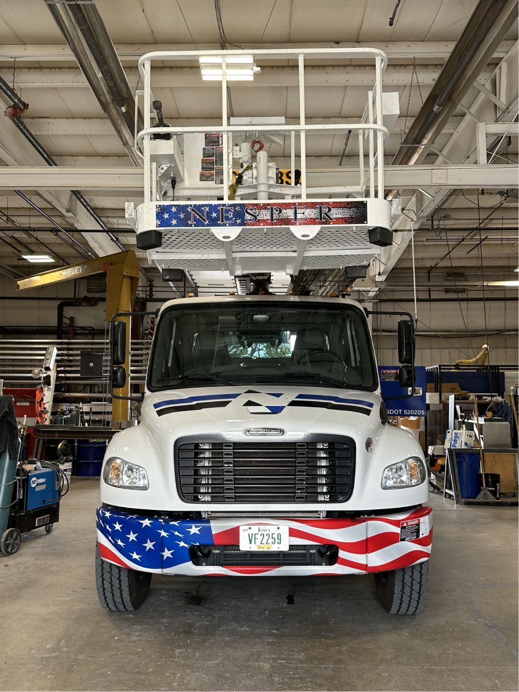 A white truck with an american flag painted on the front is parked in a garage.
