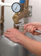 Person using a wrench to repair a water heater