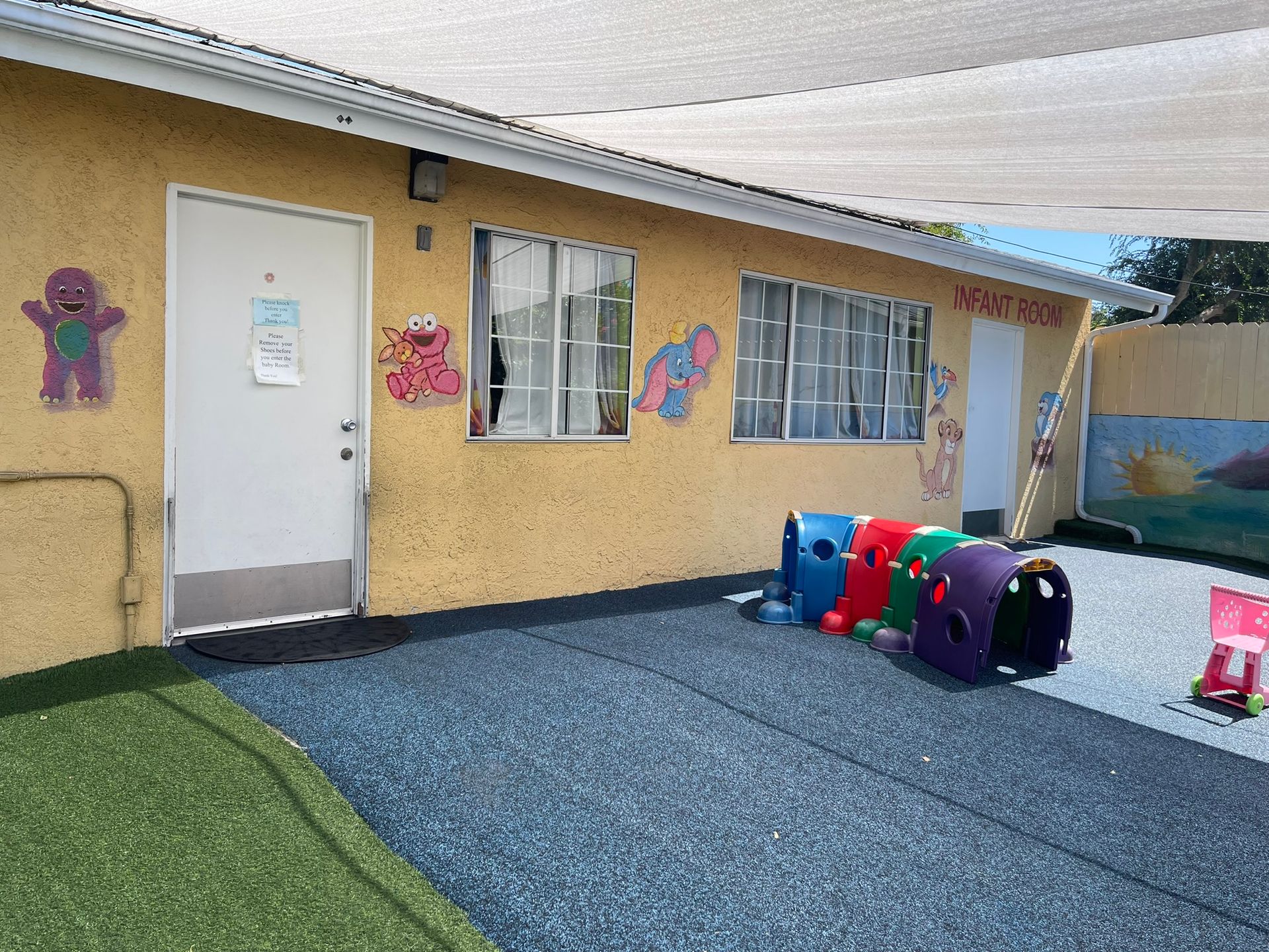 A yellow building with a white door and a bunch of toys in front of it.