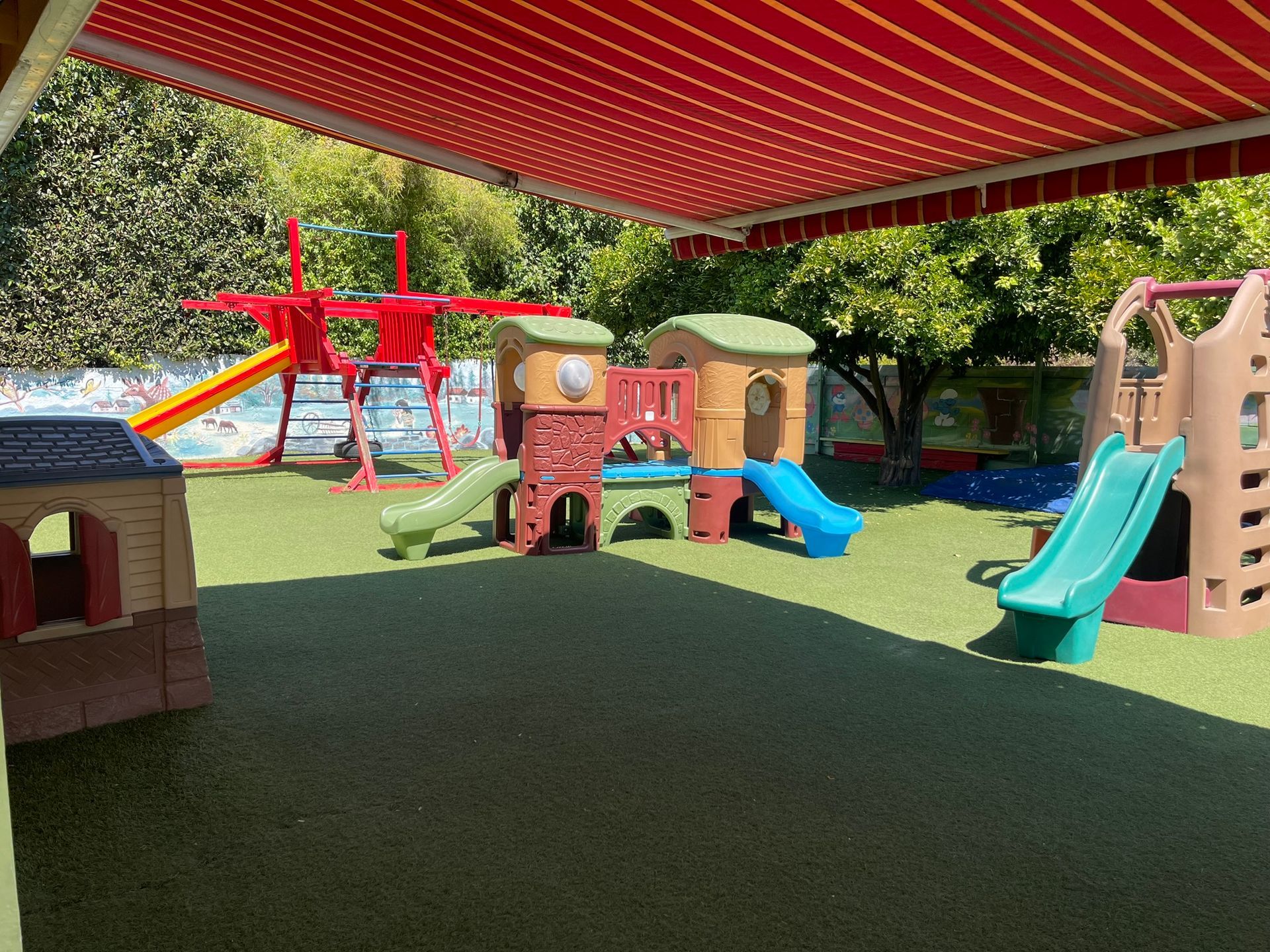 A playground with a red and yellow awning over it