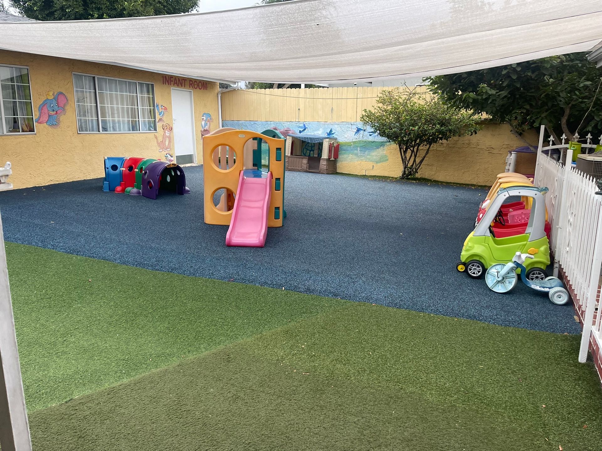 A playground with a slide , tunnel , and car.