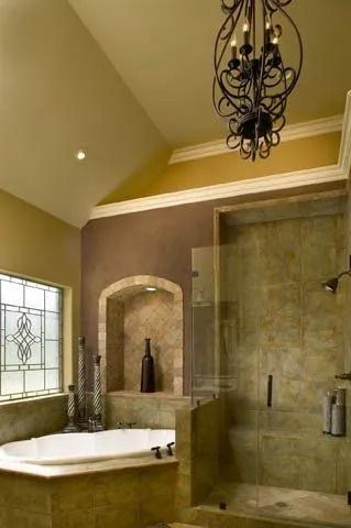 Luxurious bathroom with a bathtub, glass shower, beige walls, and a black chandelier.