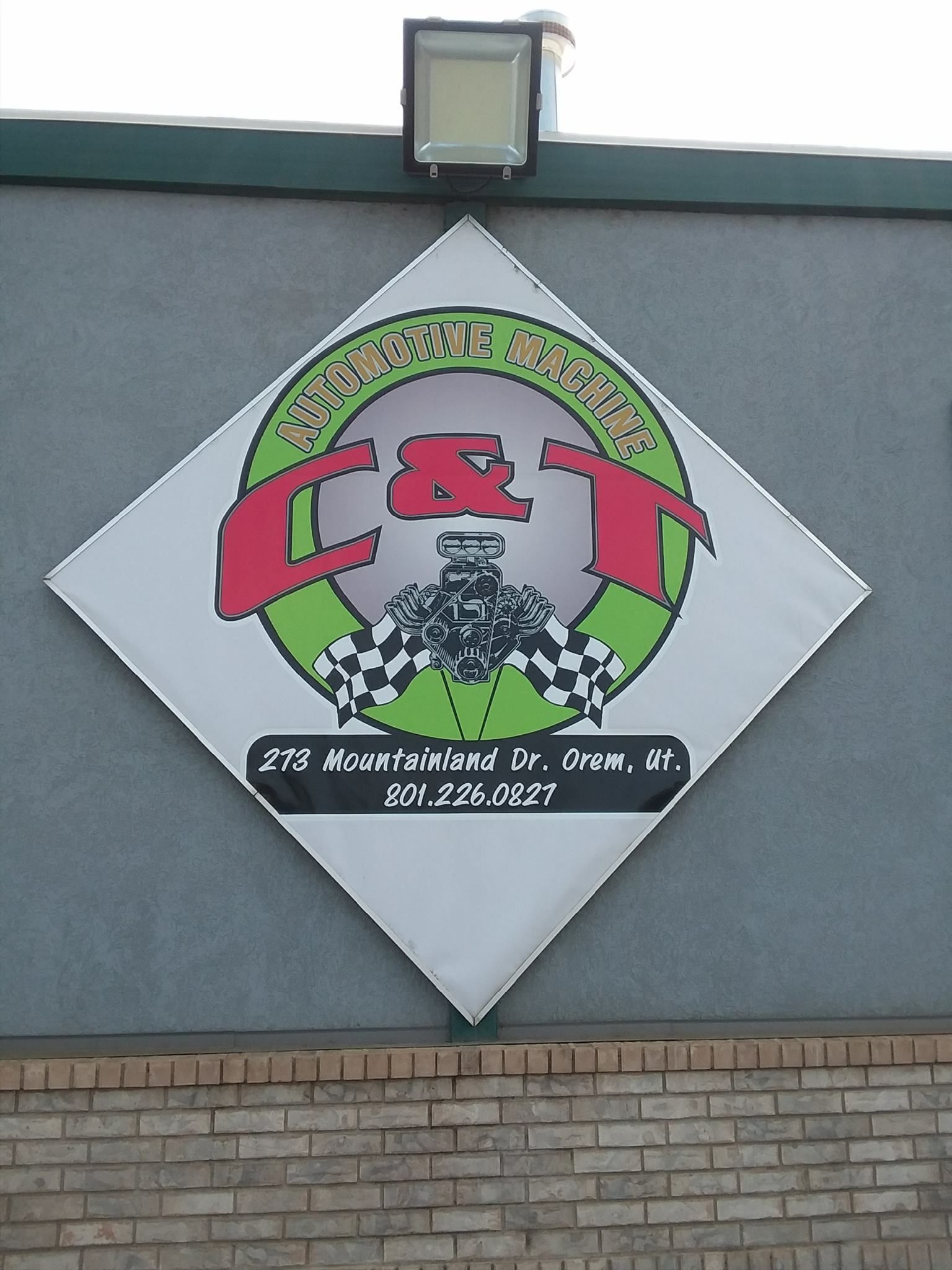 A diamond-shaped sign on a brick building featuring the logo 