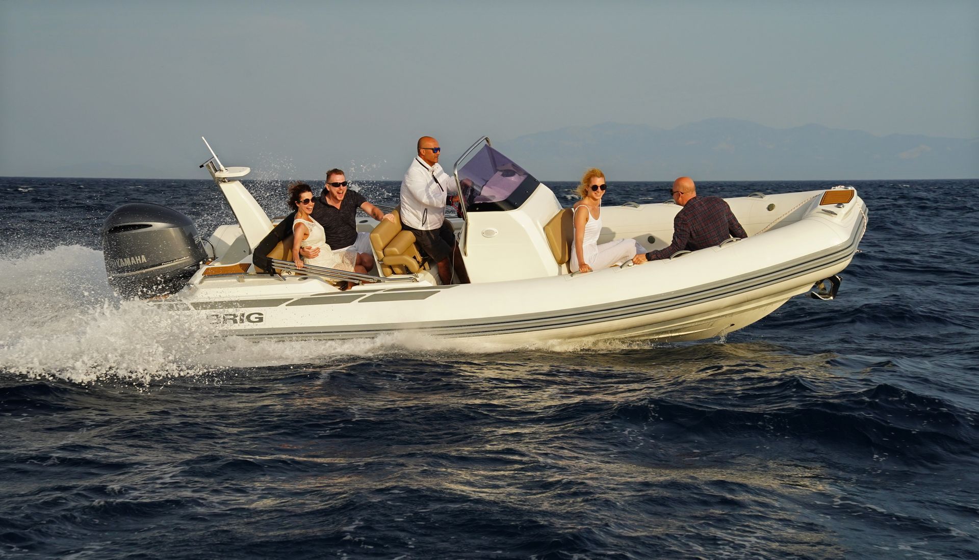 Small white motorboat speeding on choppy sea with several people aboard and spray trailing behind
