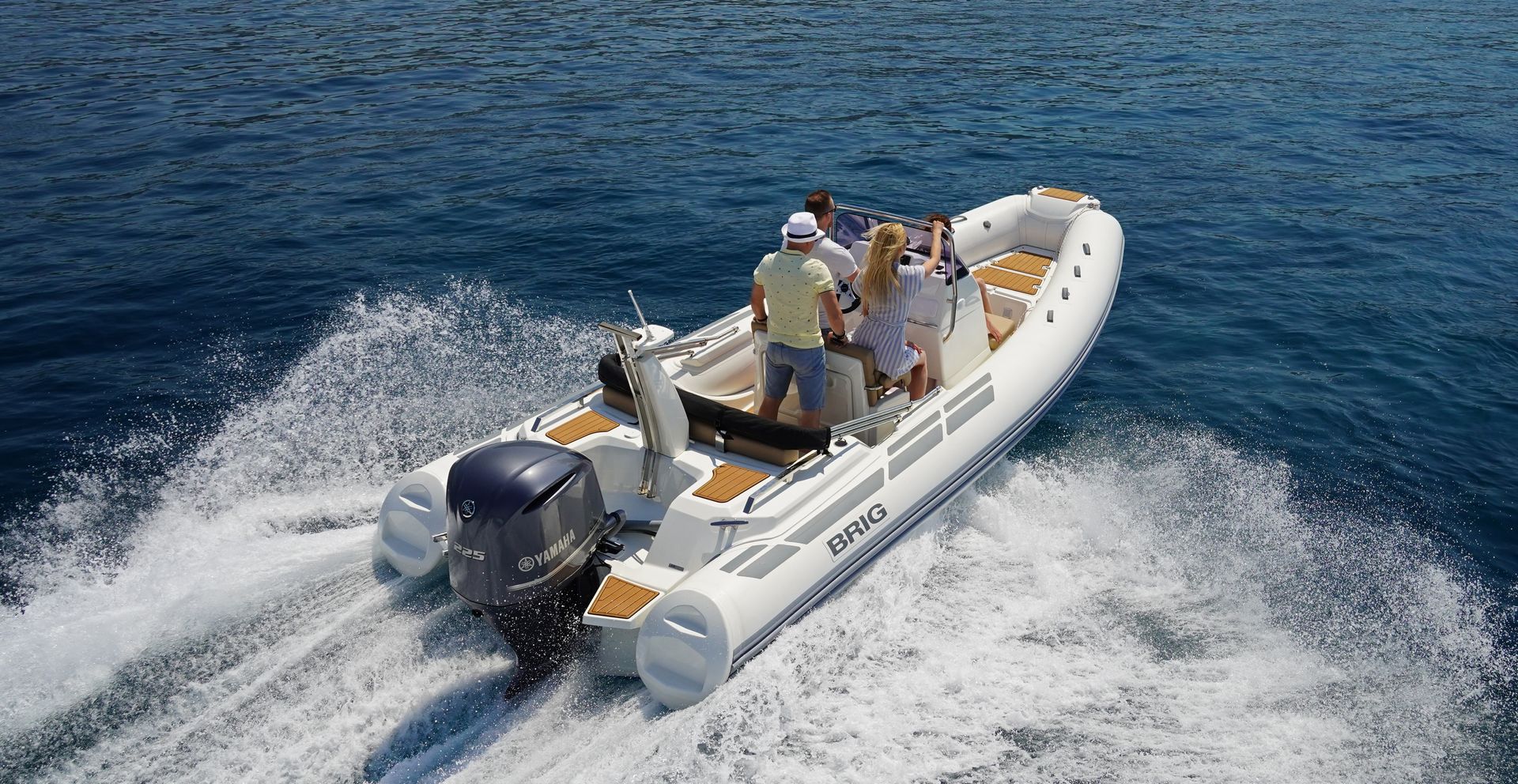 Inflatable motorboat speeding across blue water, leaving a white wake behind.