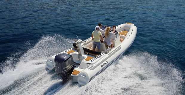 People riding a white motorboat speeding across choppy blue water, creating a large wake
