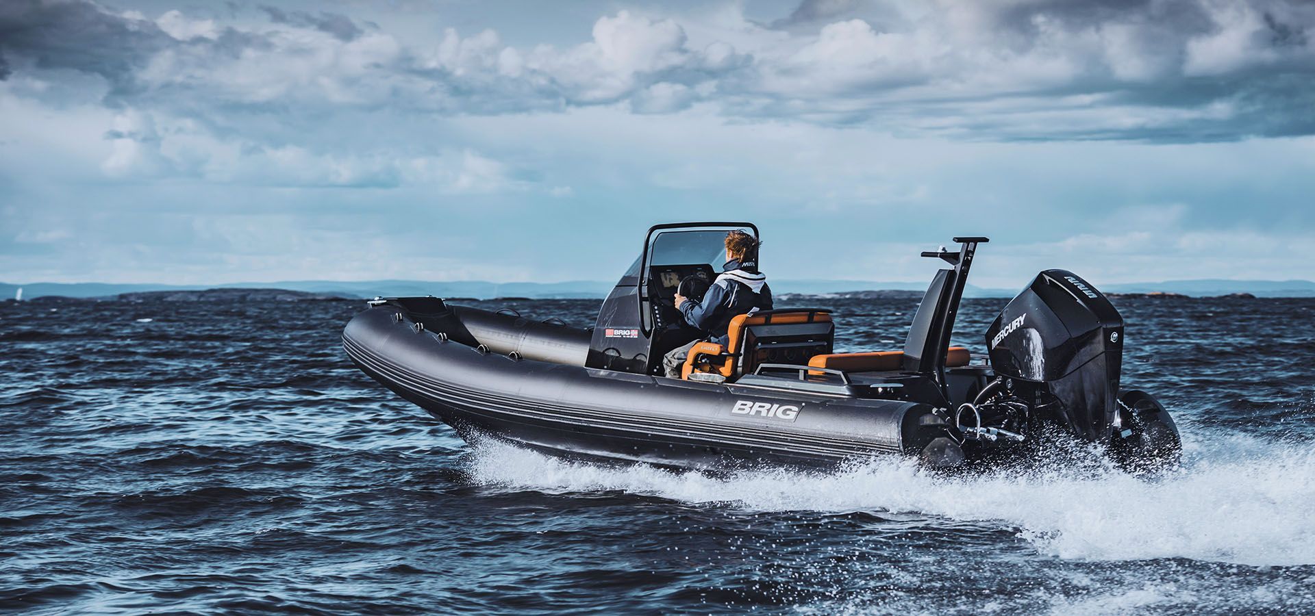 Black inflatable motorboat speeding across choppy water with a person at the helm