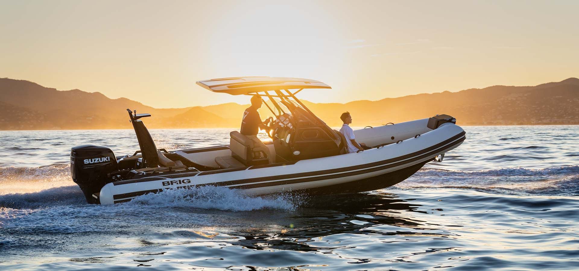 Motorboat speeding across calm water at sunset with two silhouetted passengers and mountains in the background