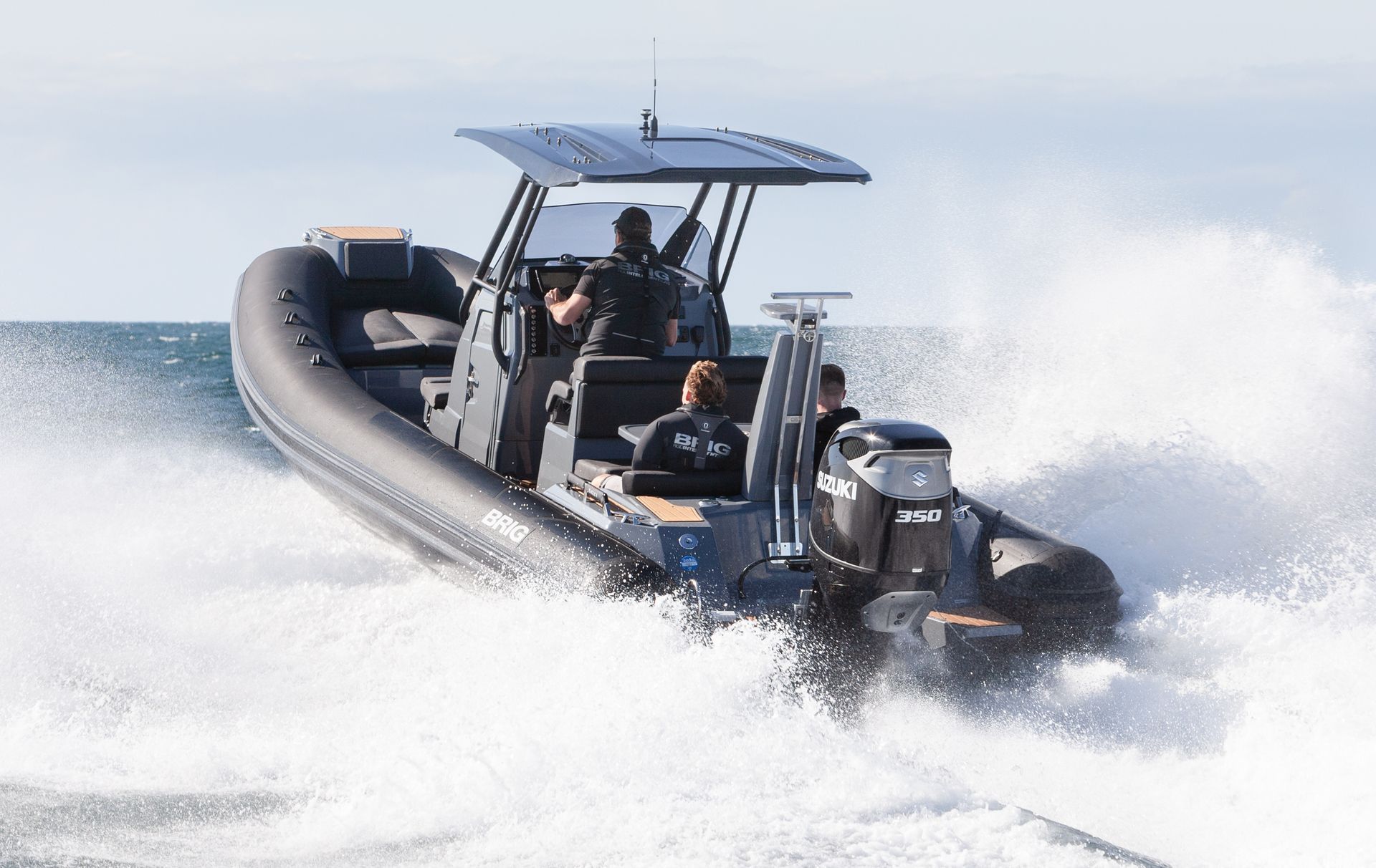 Two people ride a black speedboat speeding through choppy water, spraying white foam