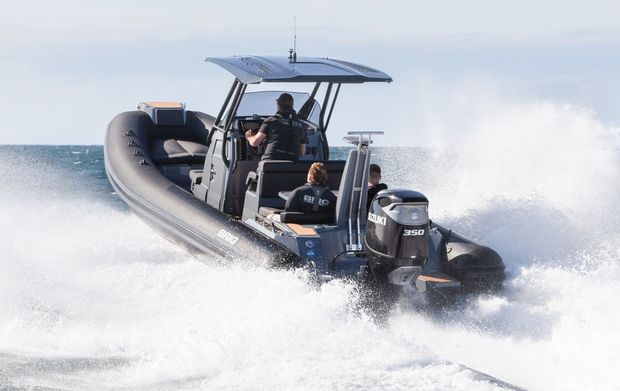 Black speedboat racing across choppy water, spraying white foam under a blue canopy