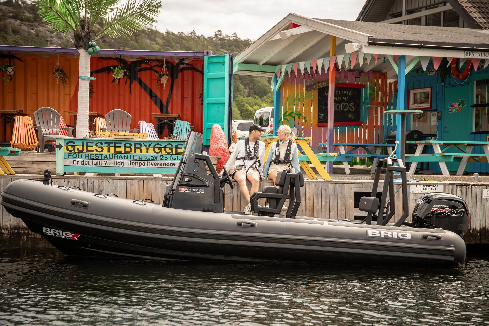 Two people in a black inflatable boat on a canal by colorful waterfront buildings