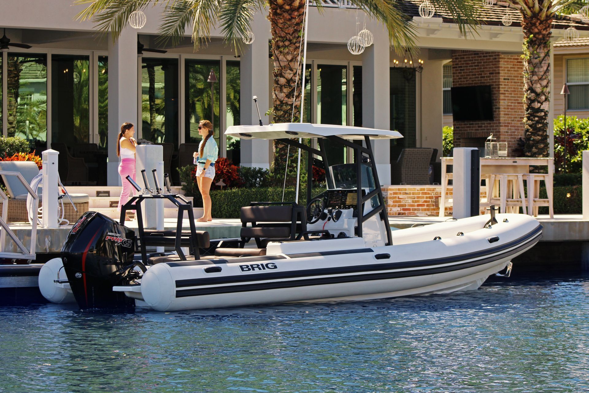 White inflatable boat docked at a resort waterfront with people standing nearby