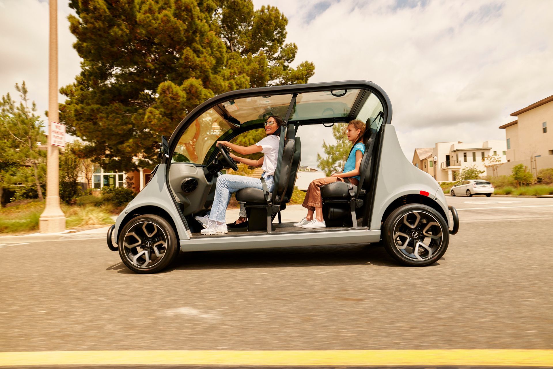 Open-sided electric car driving on a street with four passengers inside