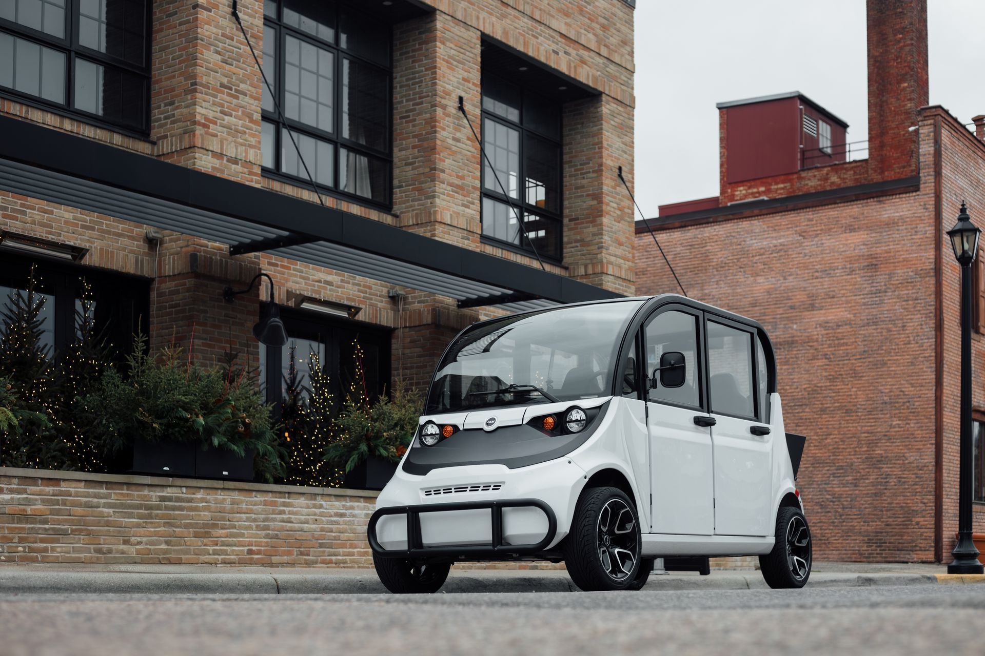 White compact electric car parked on a brick street beside modern townhouses