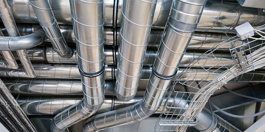 A bunch of metal pipes are hanging from the ceiling of a building.