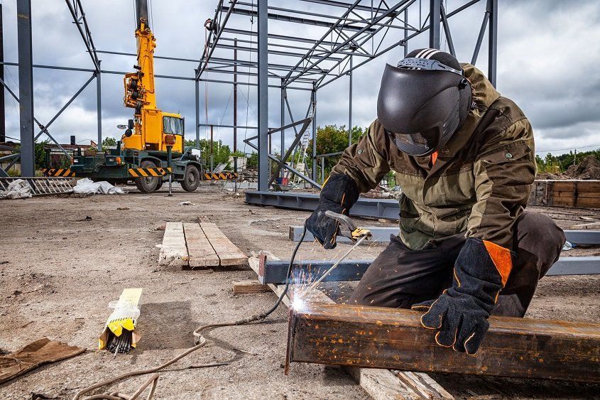 A man is welding a piece of metal on a construction site.