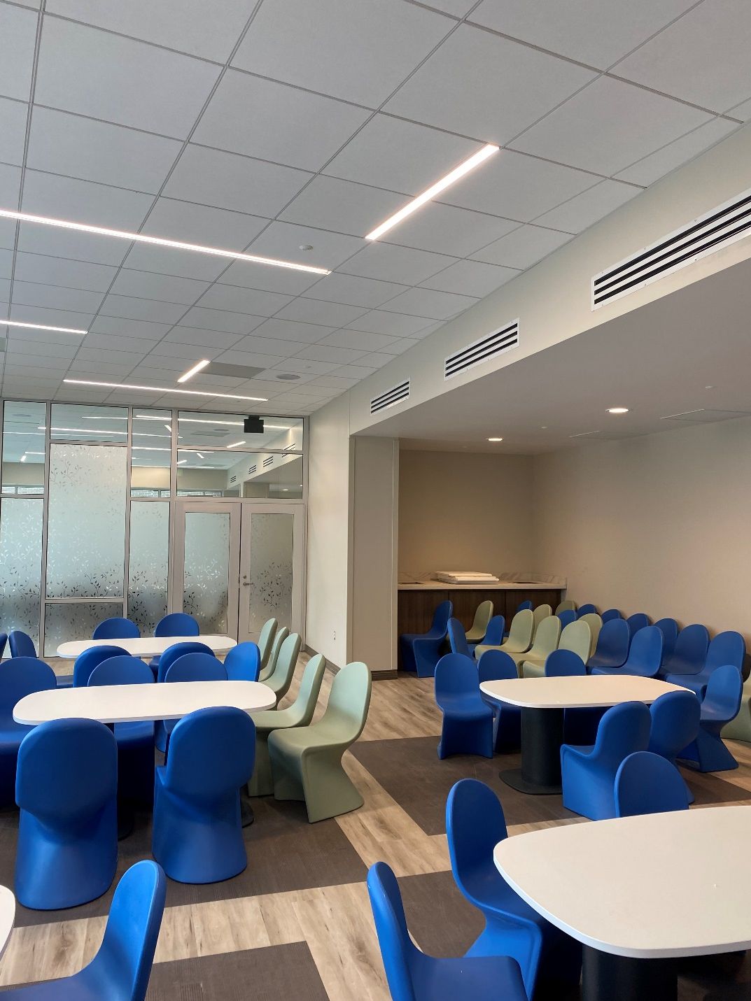 A dining room with blue chairs and white tables
