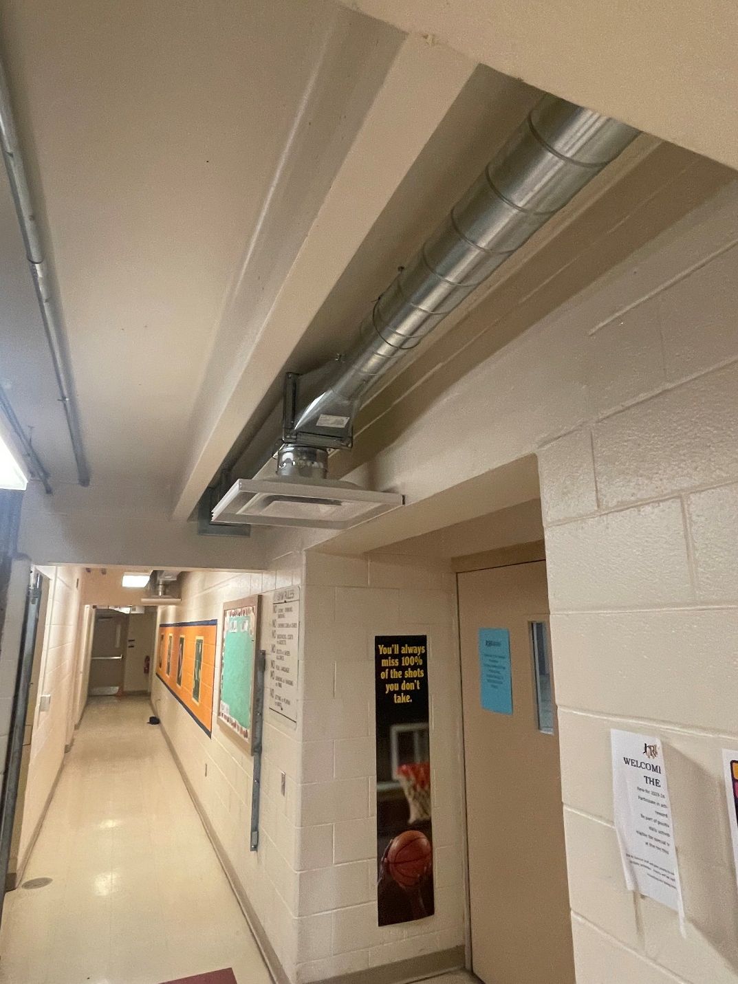 A long hallway with a metal pipe hanging from the ceiling.