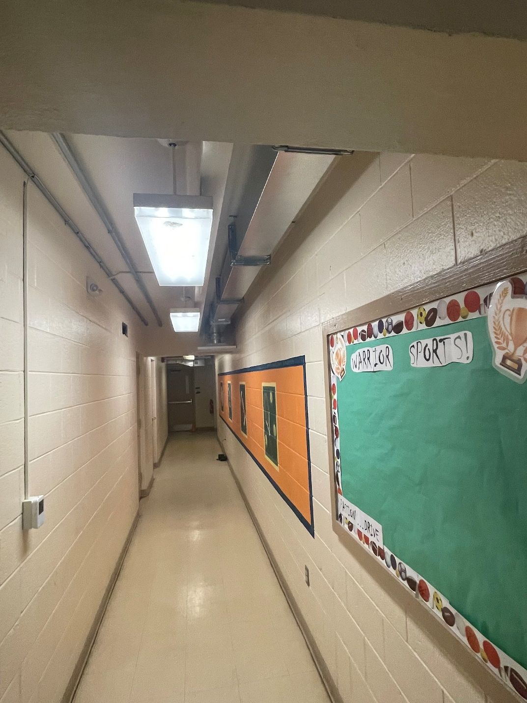 A long hallway with a green bulletin board on the wall
