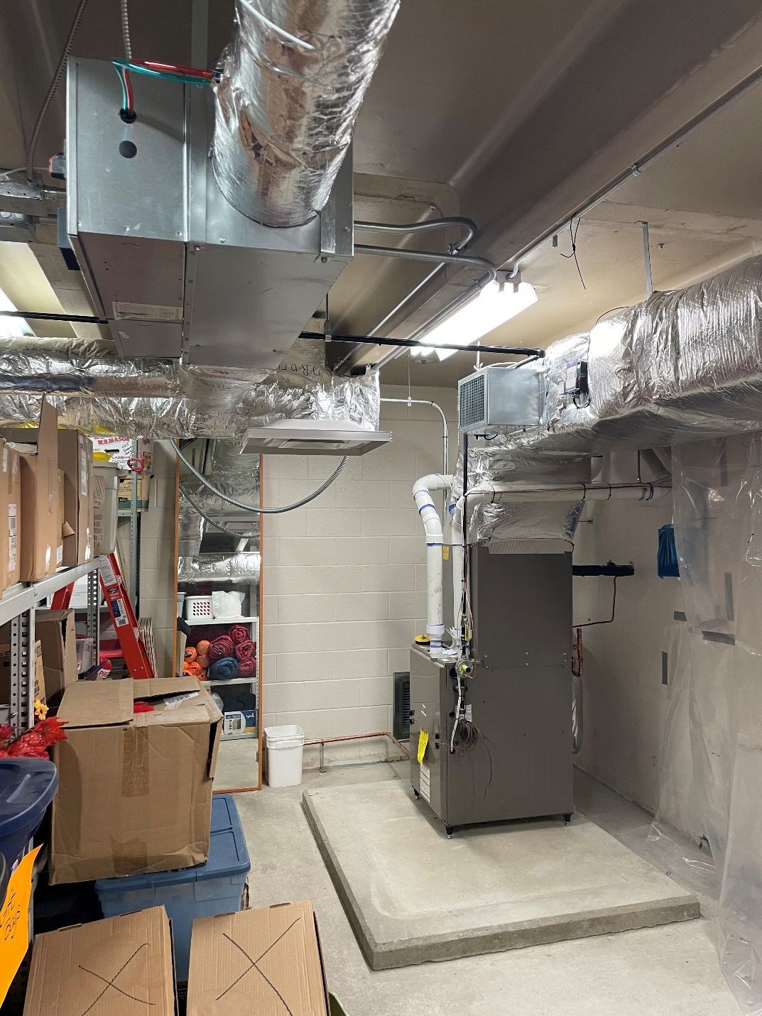 A room with a heater and a lot of pipes coming out of the ceiling.