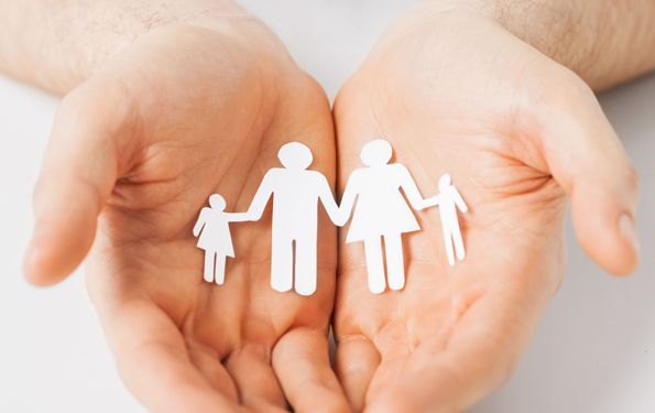 A person is holding a paper cut out of a family in their hands.