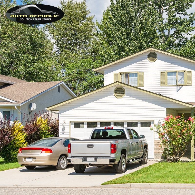 A silver truck is parked in front of a white house