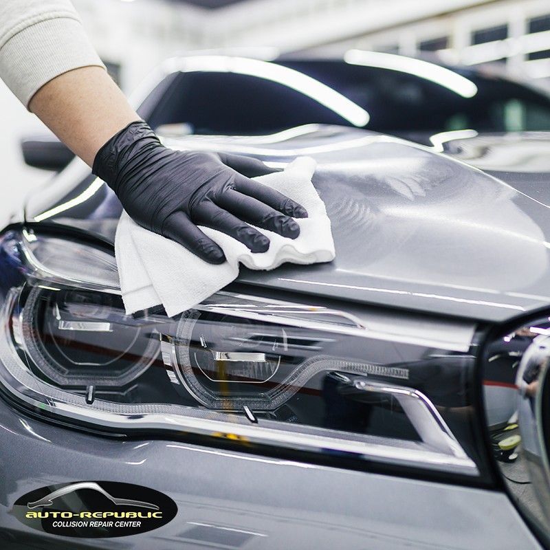 A person wearing black gloves is cleaning a car with a cloth