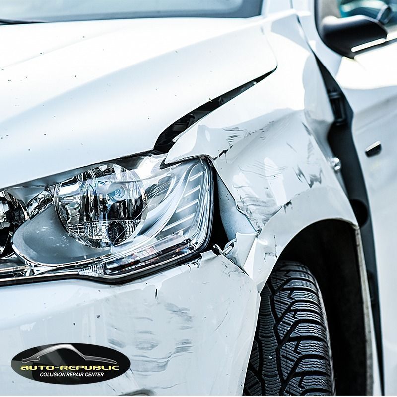A white car with a damaged fender and headlight.