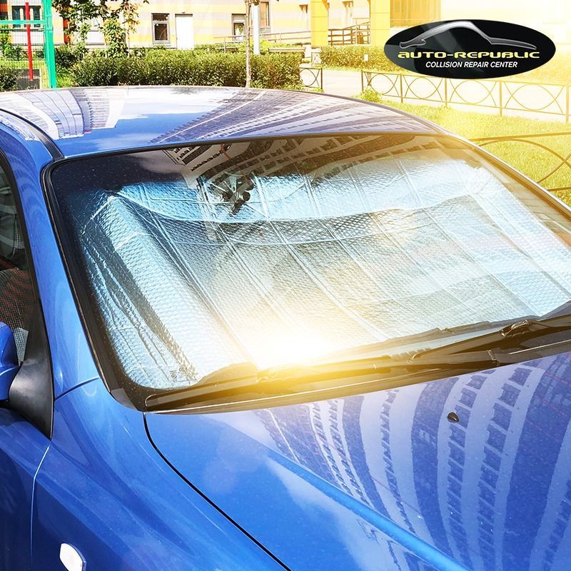A blue car with a sun shade on the windshield