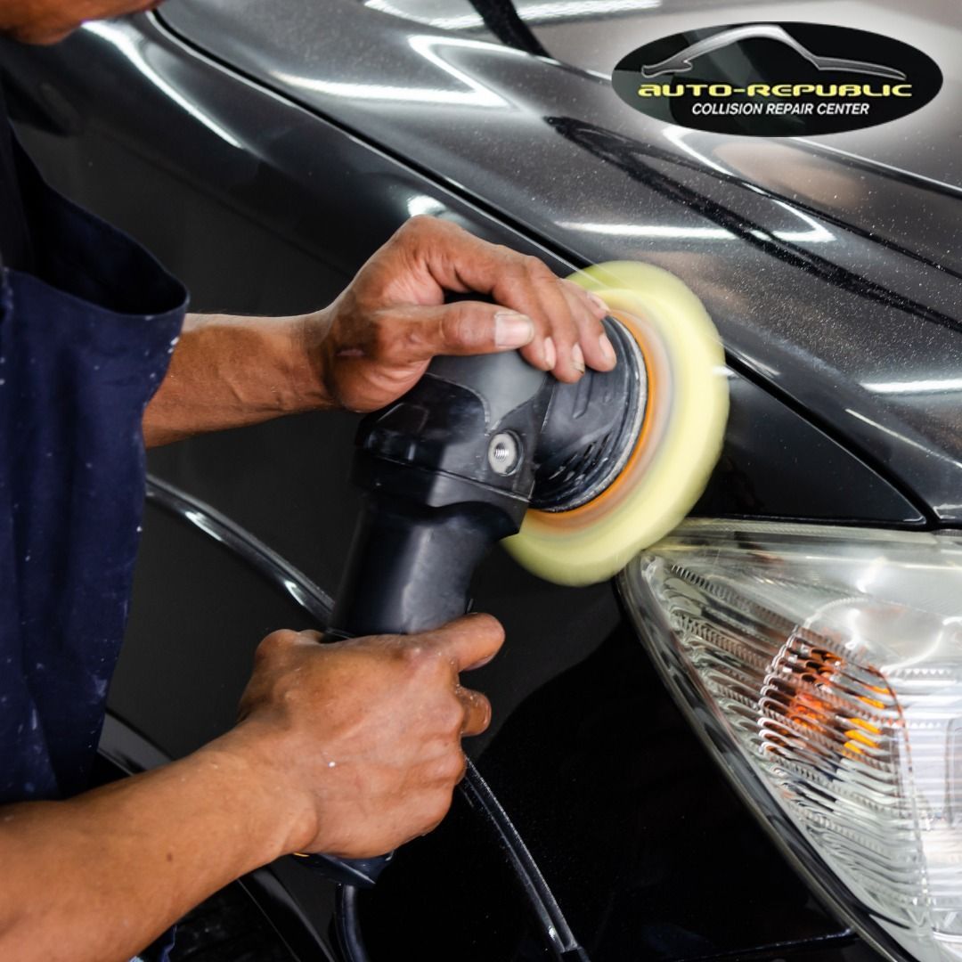A man is polishing a car with an auto republic logo in the background