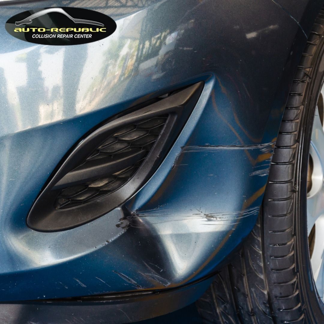 A close up of a blue car with a damaged bumper