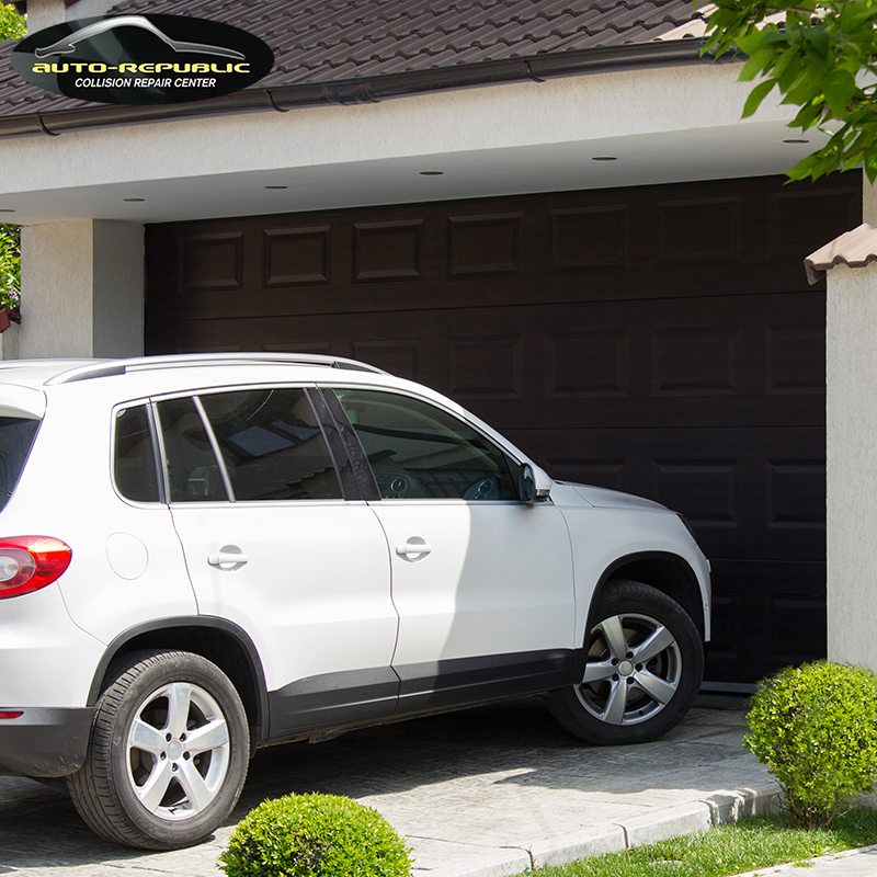 A white suv is parked in front of a garage door